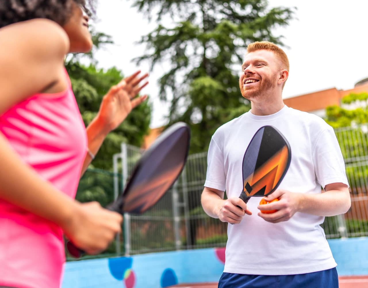Pickleball coach and player smiling during a lesson on an outdoor court